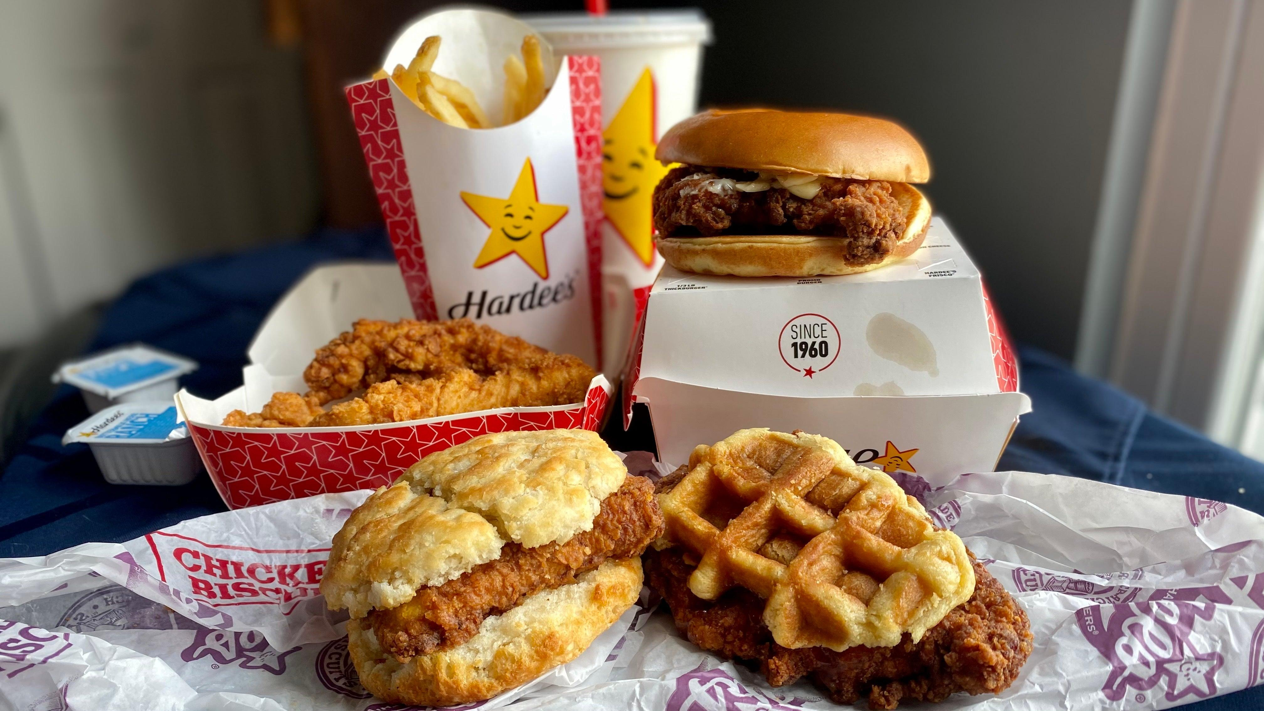 Table displaying Hardee's fries, fountain drink, tenders, and three new chicken sandwiches