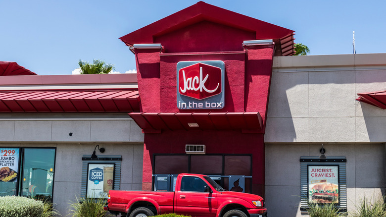 Exterior of a Jack in the Box location, with a red pickup truck parked at the drive-thru window