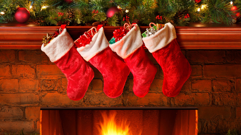 four red Christmas stockings hanging over a fireplace