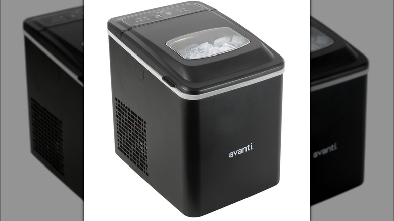 A boxy black ice maker with an Avanti logo and ice visible through a window on the lid on a white background.