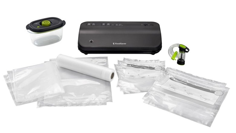 A small, black gadget surrounded by sealable bags and a Tupperware-style container on a white background.
