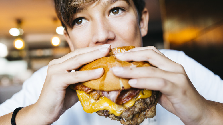 Person eating a double cheeseburger
