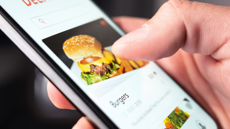 Person reading restaurant menu, website and reviews with smartphone.