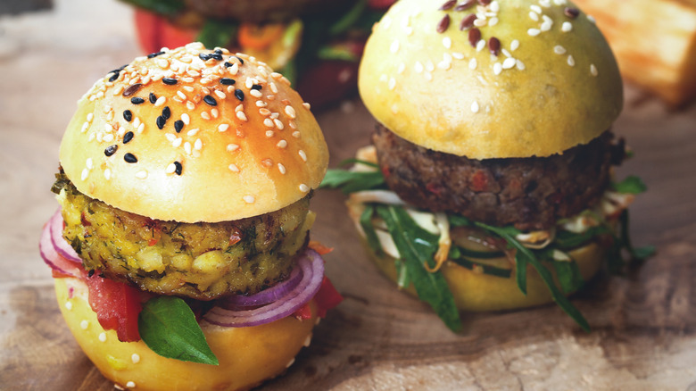 Two small burgers on a wooden platter