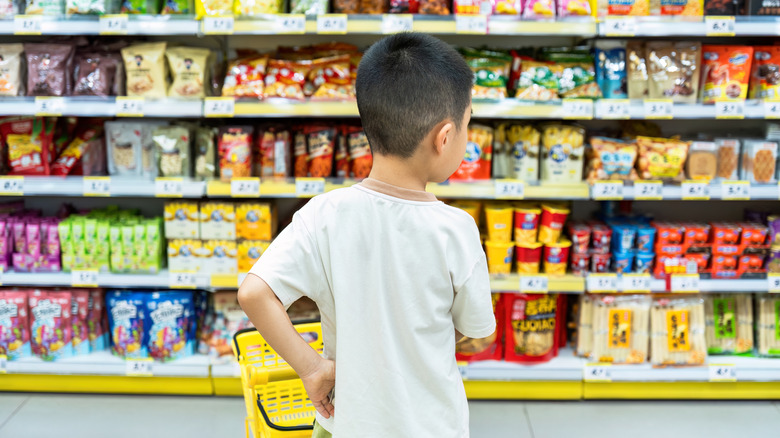 A child in the candy aisle with a basket