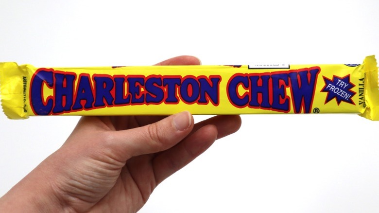 A hand holding a Charleston Chew bar against white background