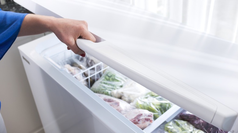 A woman opening a freezer.