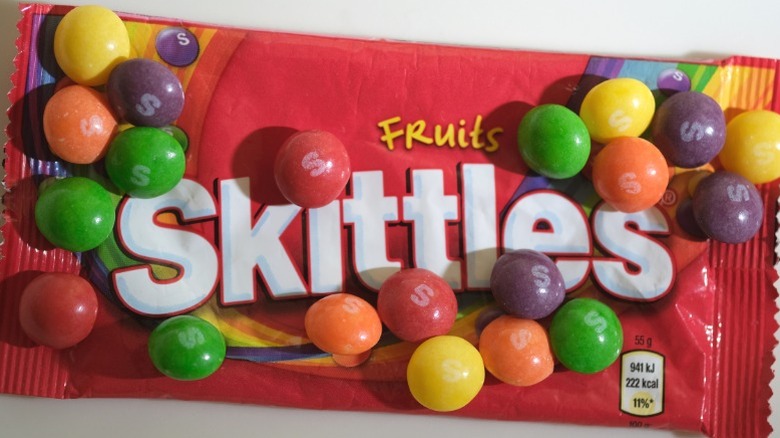 Close-up of a Skittles wrapper with Skittles on top.