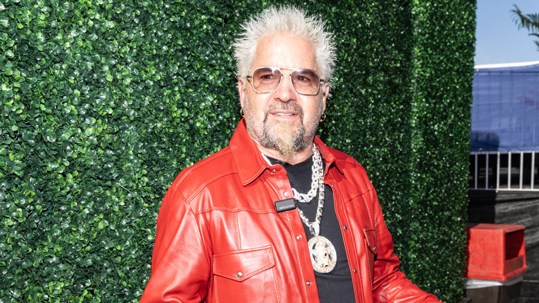 Guy Fieri wearing a red leather jacket and sunglasses