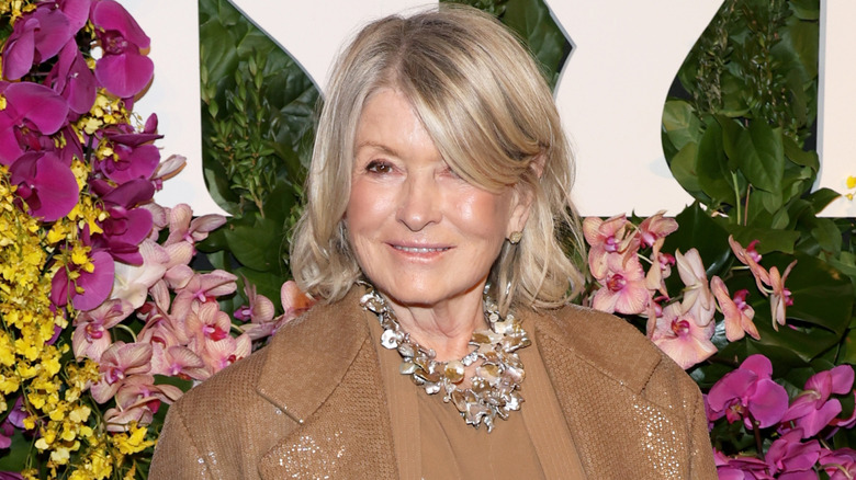 Martha Stewart posing in front of a wall of flowers