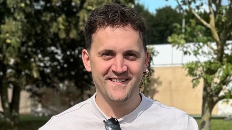 Jon Watts smiling in front of trees