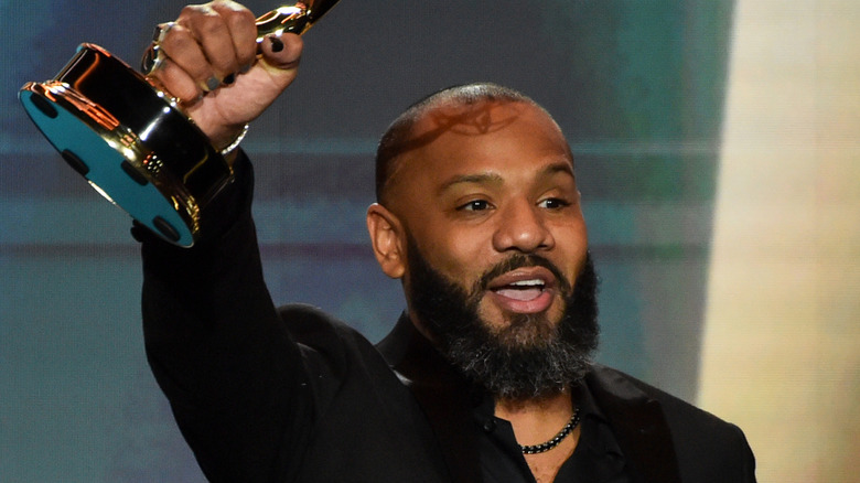 Justin Sutherland holding Emmy aloft