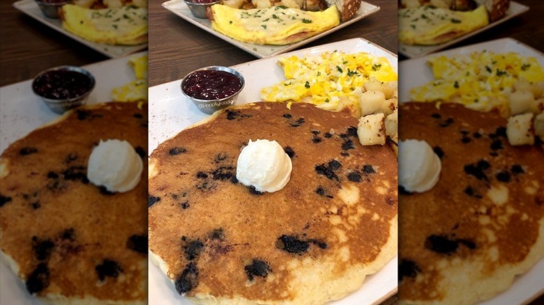 First Watch's Blueberry Pancakes with butter on top and eggs, potatoes, and blueberry sauce on the side