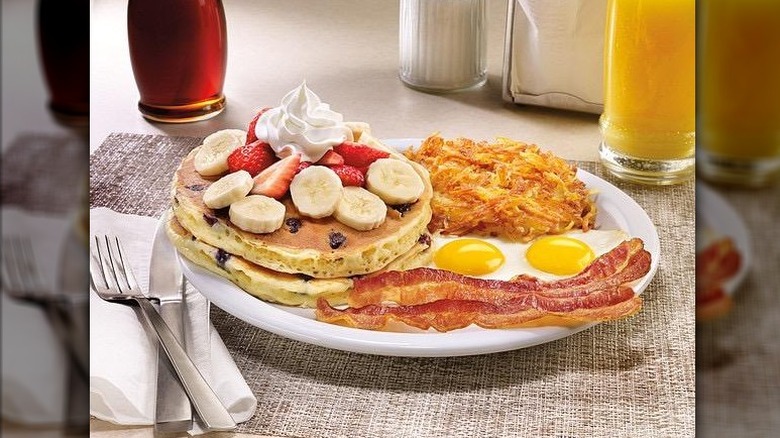 Denny's Double Berry Banana Pancakes paired with hash browns, eggs, and bacon