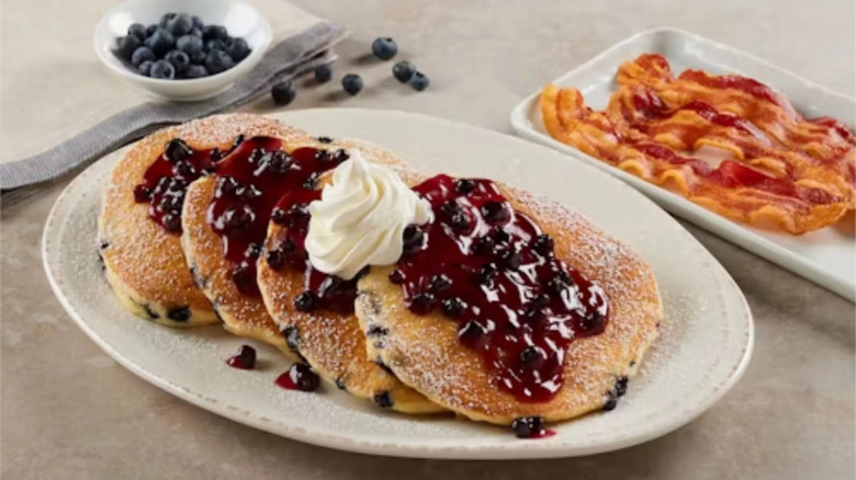 Four of Bob Evans Double Blueberry Pancakes laid out on a plate and topped with whipped cream.