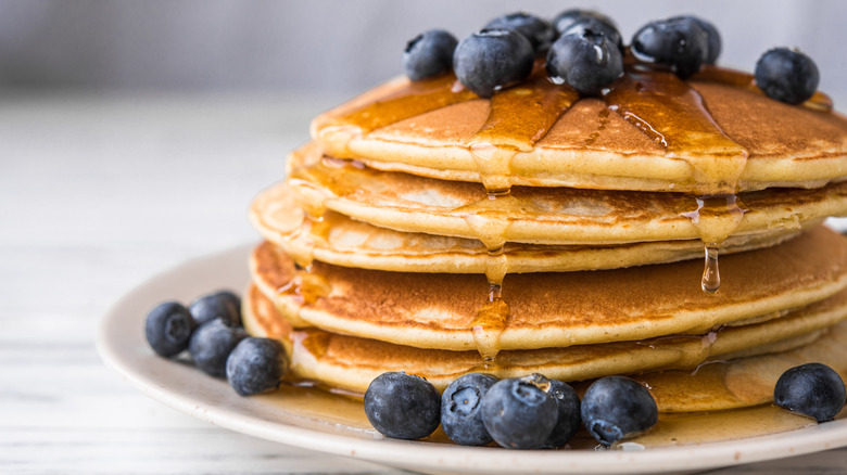A stack of pancakes topped with blueberries and syrup