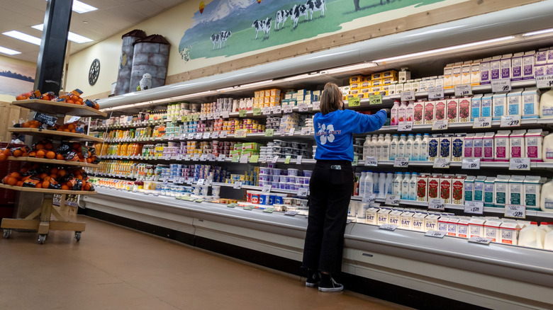Trader Joe's crew member stocking refrigerated dairy section