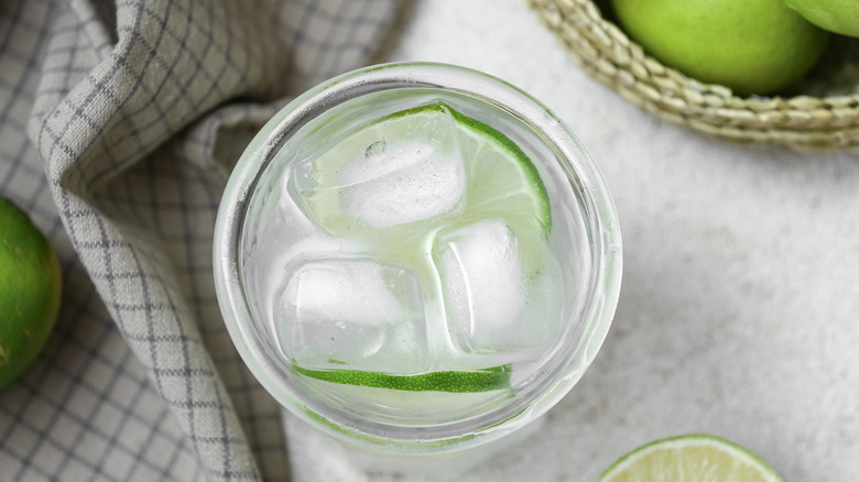 Glass of lime infused water on white background