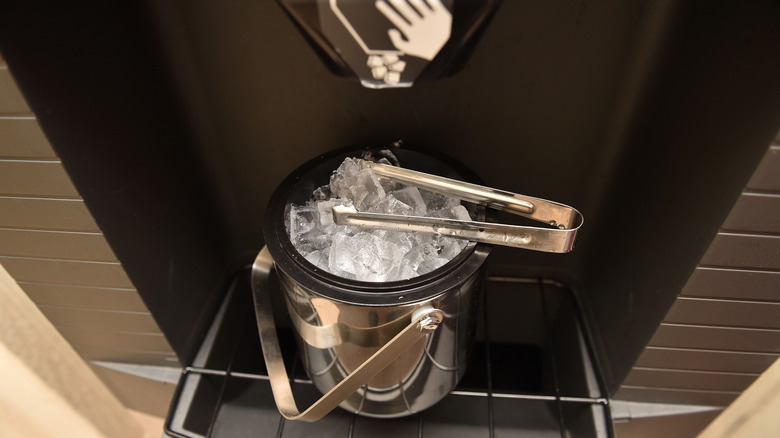 Ice cubes in an ice bucket under the spout of an ice machine