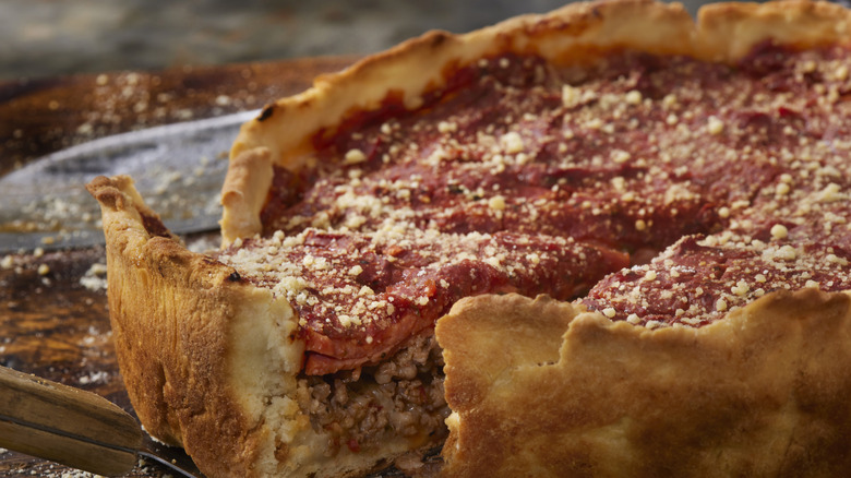 A close up image of a Chicago style deep dish pizza with a slice being lifted