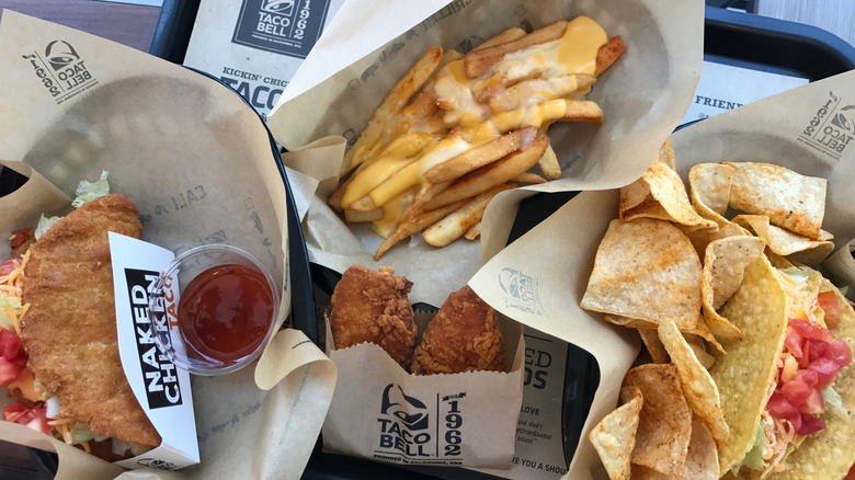 A Taco Bell meal on a tray, including a Naked Chicken Taco and fries with nacho sauce