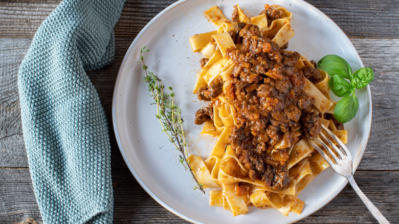 Duck ragu with tagliatelle on a white plate with a fork