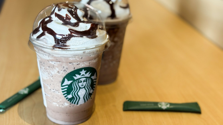 Two Starbucks Frappuccinos with whipped cream and chocolate drizzle