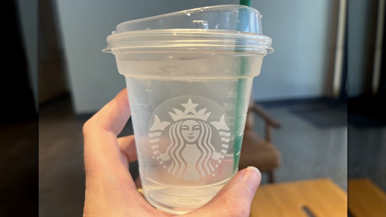 Hand holding plastic cup of Starbucks water
