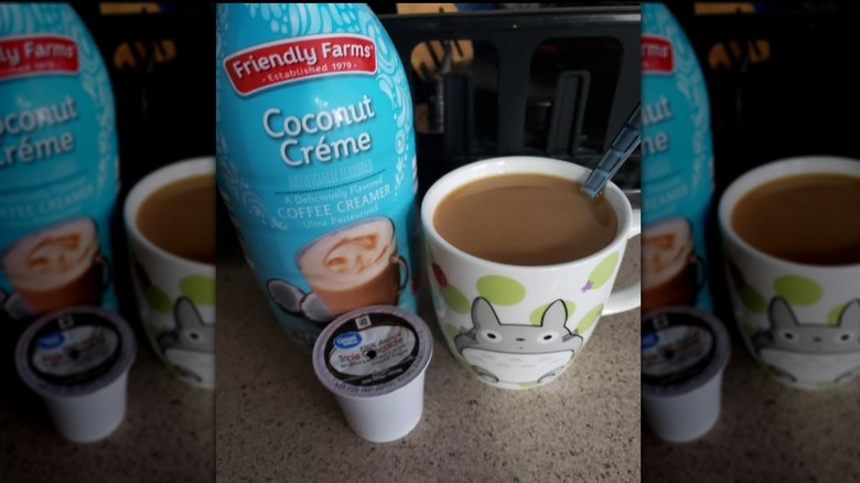 A bottle of Friendly Farms Coconut Créme Coffee Creamer next to a full coffee mug and used coffee pod