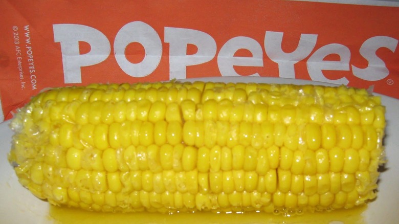 A buttery ear of corn in front of a Popeyes bag