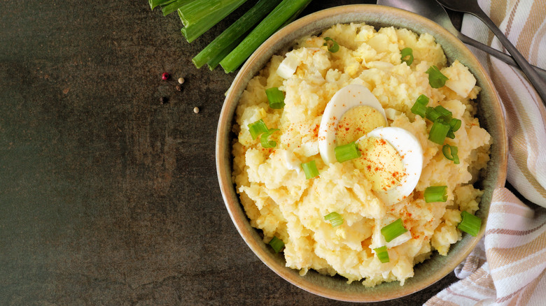 Traditional potato salad in a bowl with boiled egg and scallions