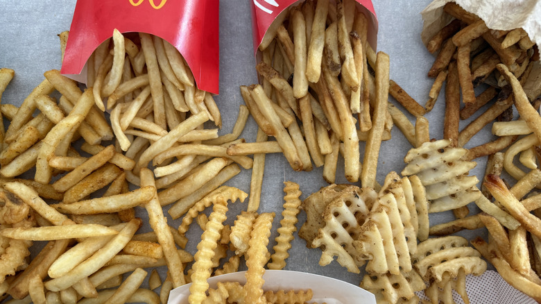 Different fast food fries scattered all over table