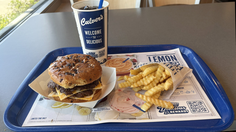 A tray with a Culver's burger, french fries, and a soda on it.