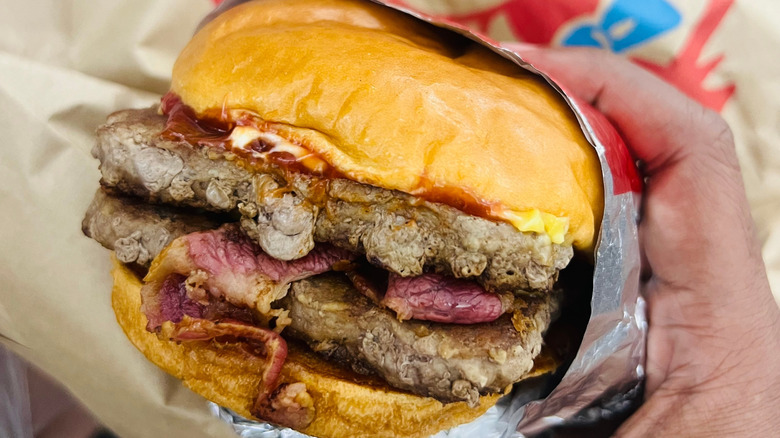 A hand holding a Wendy's double burger