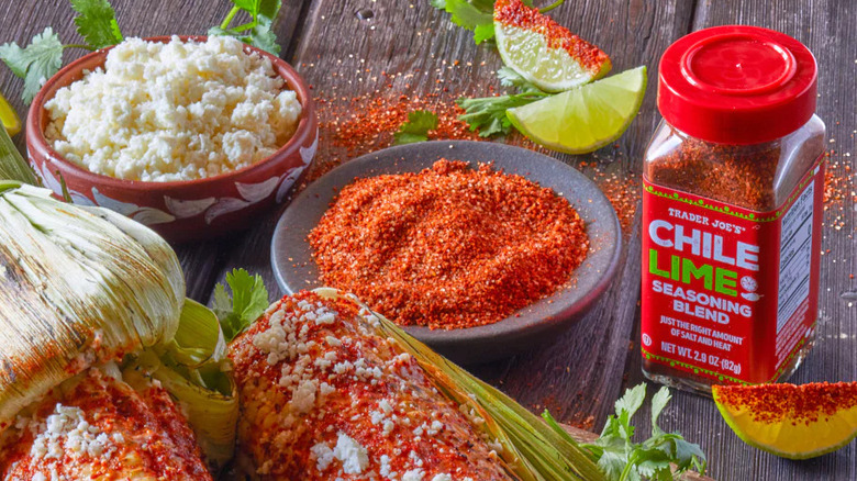 Trader Joe's Chile Lime Seasoning Blend alongside queso fresco, roasted corn, lime wedges, and cilantro