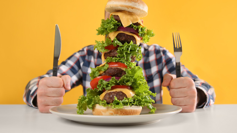 Person attempting to eat massive burger