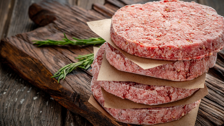 Frozen burger patties on a wood board