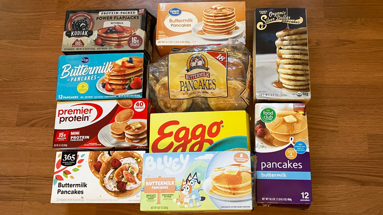 Nine boxes and one bag of frozen pancakes arranged into a square on table, including brands like Eggo, Great Value, and 365