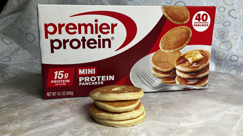 A stack of mini pancakes in front of a box of Premier frozen protein pancakes