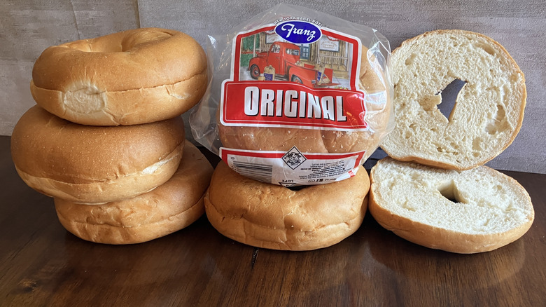 Bagels stacked next to a bag of Franz original bagels on table.
