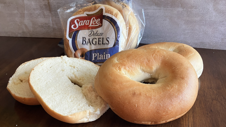 Bagels displayed in front of a bag of Sara Lee bagels on table.