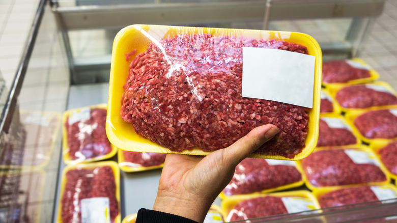 A person holding a package of raw ground meat