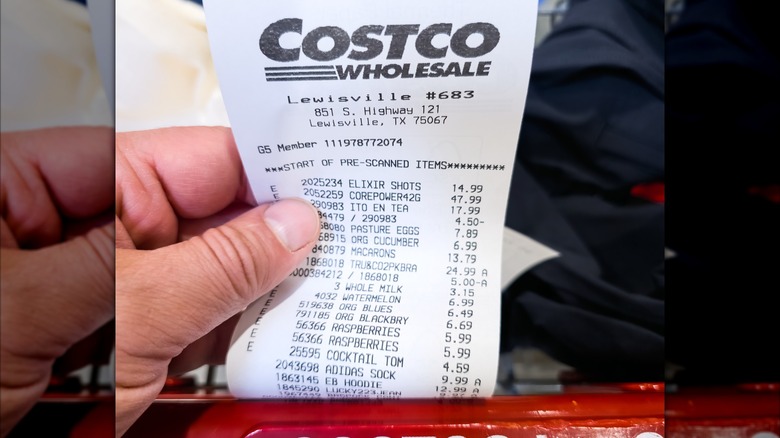 A customer holds up a Costco receipt after purchasing items at the store