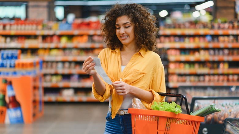 A woman looks at her receipt after shopping at a grocery store