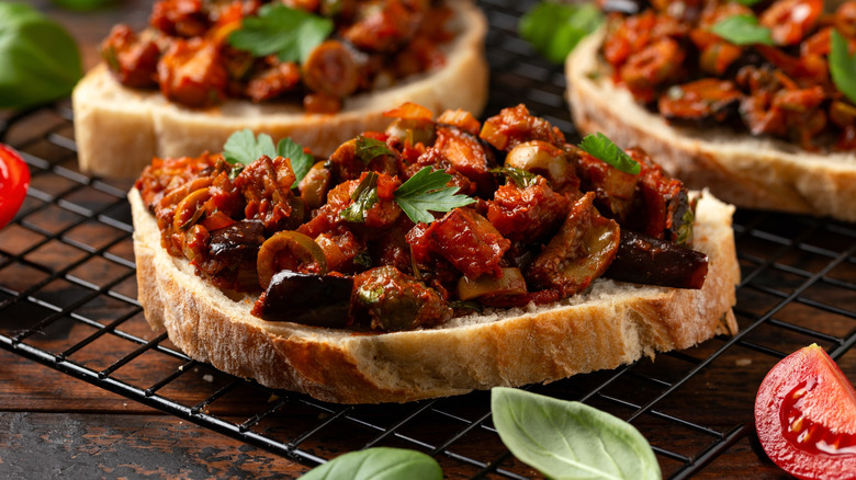 Slice of white bread holding chopped caponata mixture.