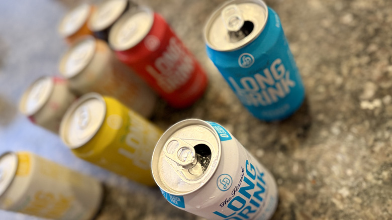 Two open Long Drink cans with other flavors of canned Long Drink in the background
