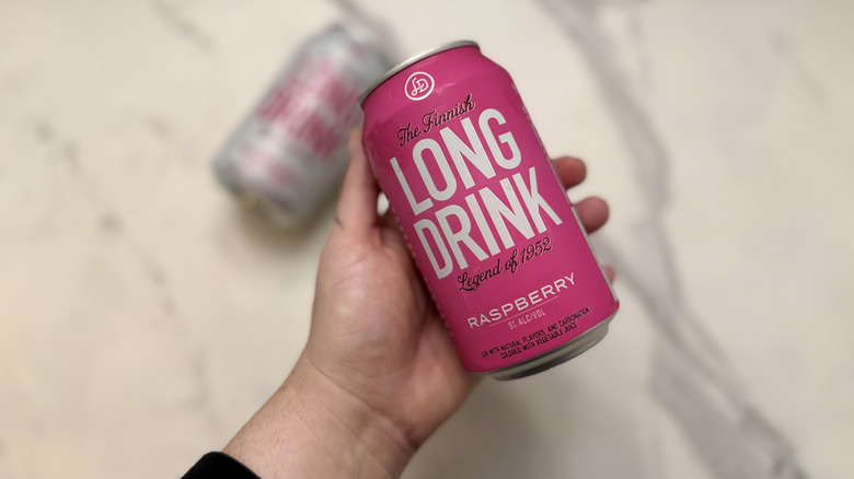 Holding a can of raspberry Long Drink in front of a zero sugar version of the drink