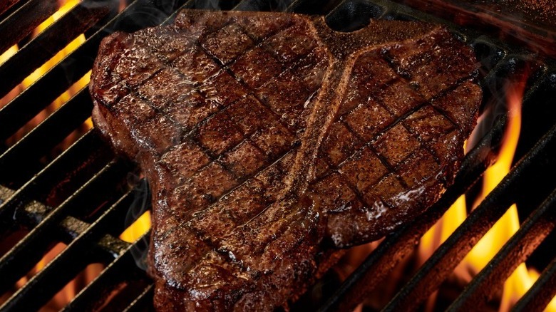 A close up of a porterhouse steak on a fire grill