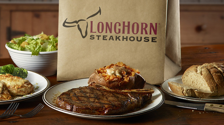 Plates of food on a table and a paper bag with the LongHorn Steakhouse logo