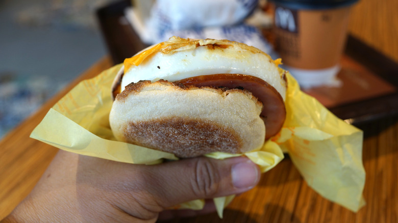 A hand holds a McDonald's breakfast sandwich